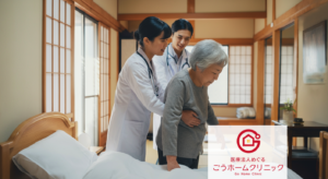 白衣の女性医師と男性医師が、グレーのセーターを着た高齢女性の腰に手を添えて移動を支援している。和風の診療室の室内。